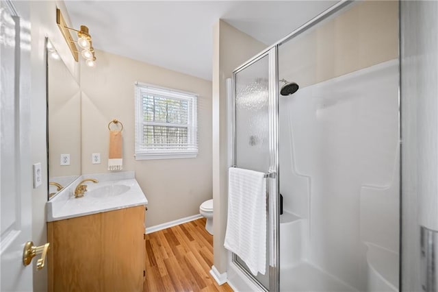 bathroom featuring hardwood / wood-style flooring, vanity, an enclosed shower, and toilet