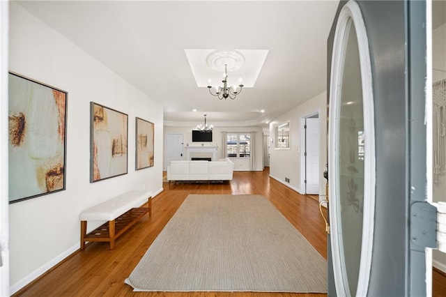 hall with hardwood / wood-style floors and an inviting chandelier