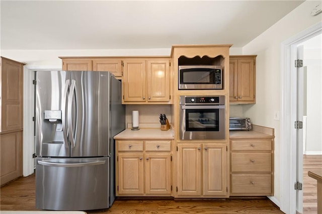 kitchen with appliances with stainless steel finishes, light brown cabinetry, and wood-type flooring