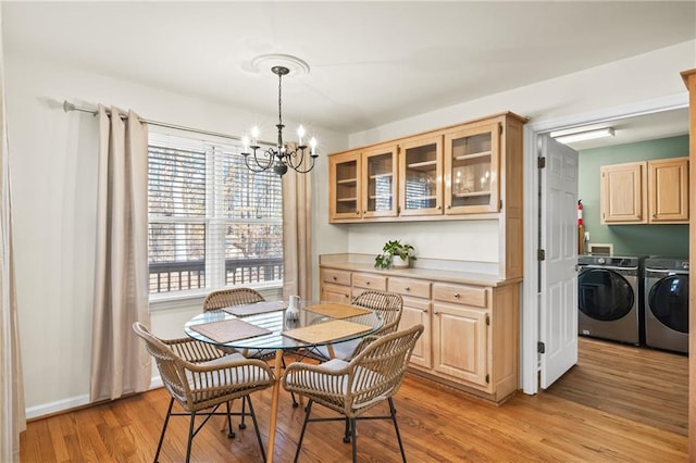 dining room featuring separate washer and dryer, an inviting chandelier, and light hardwood / wood-style flooring