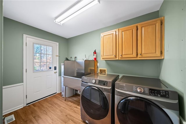 laundry room with cabinets, washer and clothes dryer, and light hardwood / wood-style floors