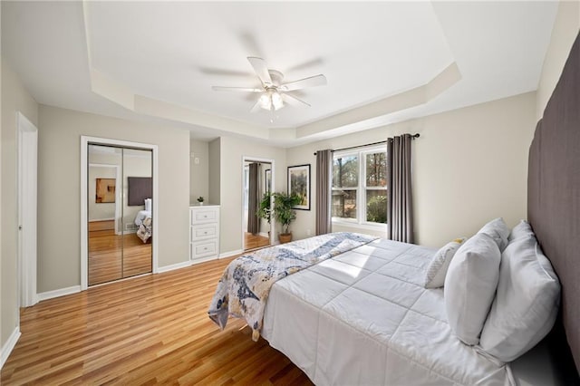 bedroom featuring hardwood / wood-style flooring, ceiling fan, and a raised ceiling