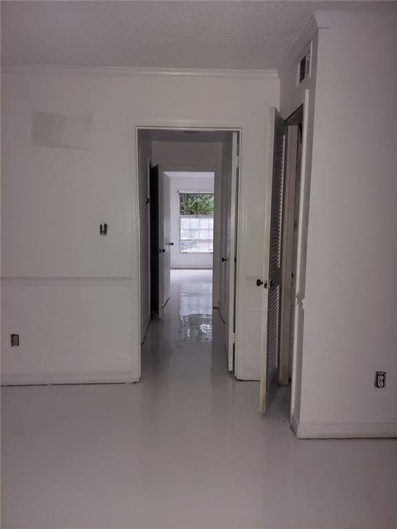 hall with ornamental molding, concrete flooring, and a textured ceiling