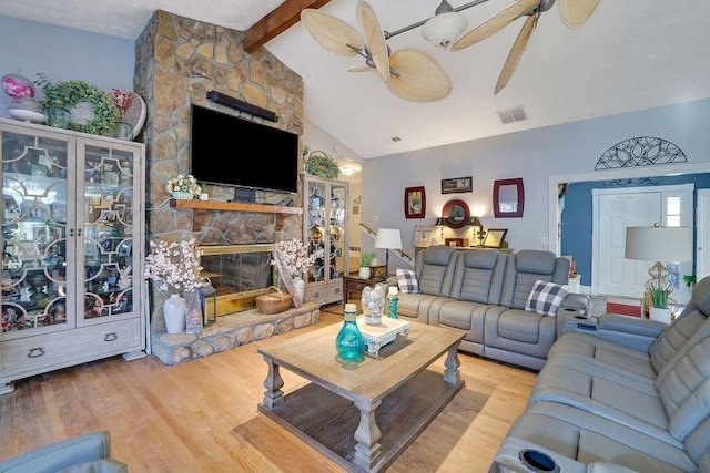 living room with a fireplace, ceiling fan, hardwood / wood-style flooring, and vaulted ceiling with beams