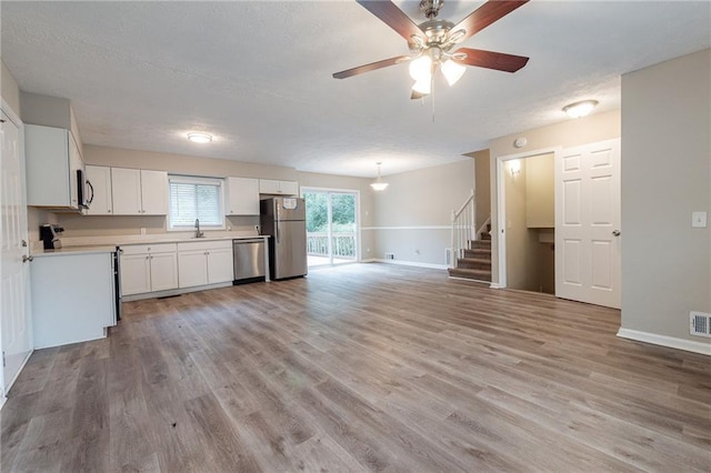 kitchen with sink, white cabinetry, light hardwood / wood-style flooring, appliances with stainless steel finishes, and ceiling fan