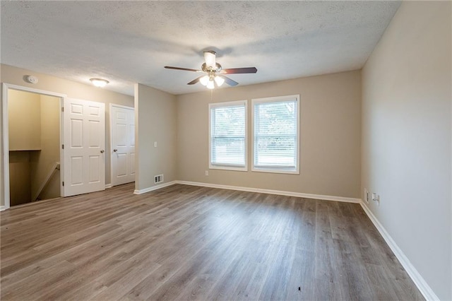 unfurnished room with a textured ceiling, ceiling fan, and light hardwood / wood-style flooring