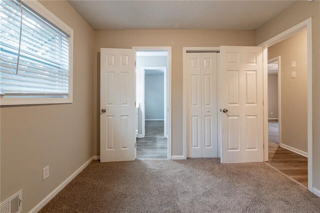 unfurnished bedroom featuring a textured ceiling, a closet, and carpet flooring