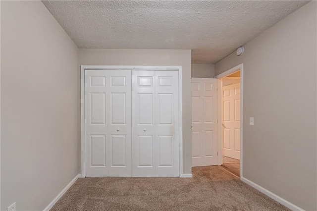 unfurnished bedroom with light colored carpet, a textured ceiling, and a closet