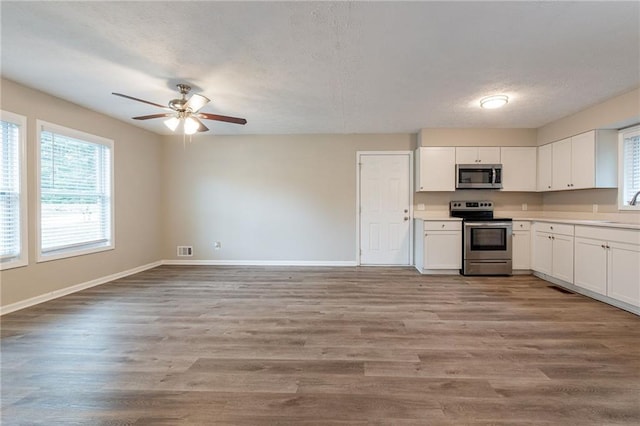 kitchen featuring ceiling fan, stainless steel appliances, light hardwood / wood-style floors, and white cabinetry