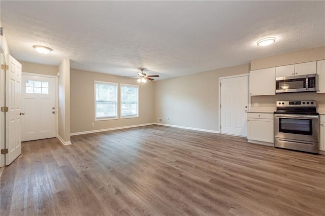 kitchen with appliances with stainless steel finishes, a healthy amount of sunlight, white cabinetry, and light hardwood / wood-style flooring