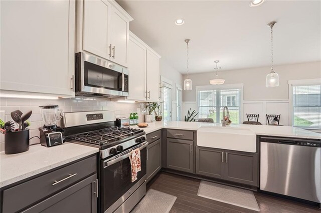 kitchen featuring appliances with stainless steel finishes, hanging light fixtures, white cabinets, gray cabinets, and sink