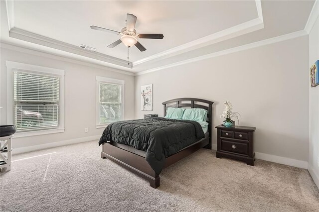 bedroom featuring a raised ceiling, ornamental molding, light carpet, and ceiling fan