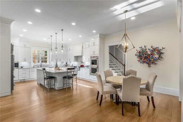 dining space with light hardwood / wood-style floors, ornamental molding, and sink