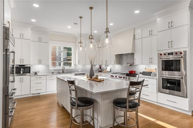 kitchen featuring backsplash, stainless steel double oven, sink, white cabinets, and a kitchen island