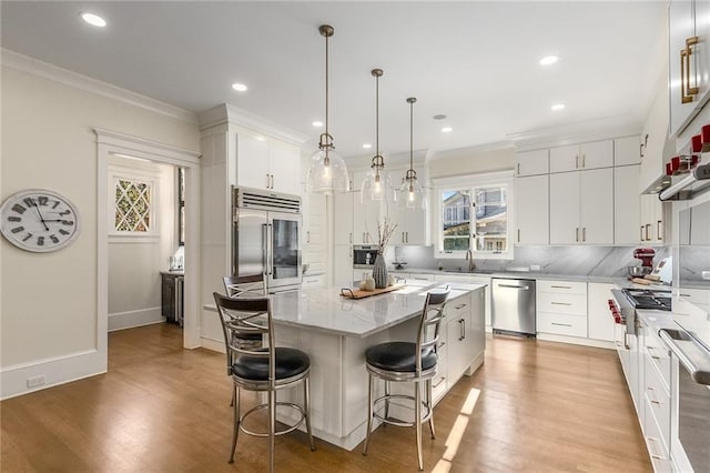 kitchen featuring white cabinetry, hanging light fixtures, decorative backsplash, a kitchen island, and appliances with stainless steel finishes