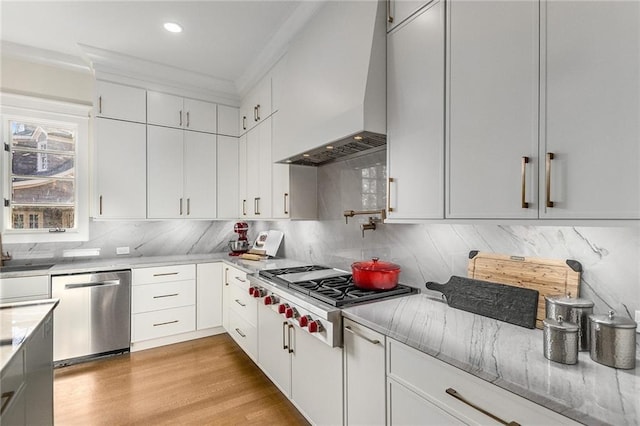 kitchen with backsplash, ornamental molding, custom range hood, stainless steel appliances, and white cabinets