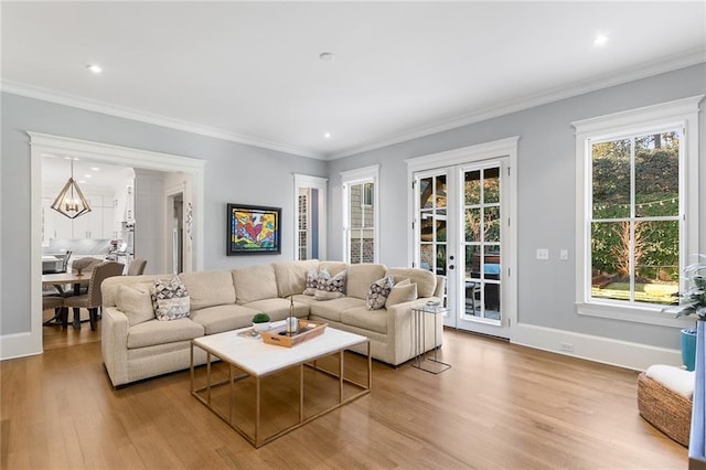 living room featuring a chandelier, french doors, light wood-type flooring, and crown molding