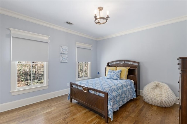 bedroom featuring hardwood / wood-style flooring, ornamental molding, and a notable chandelier