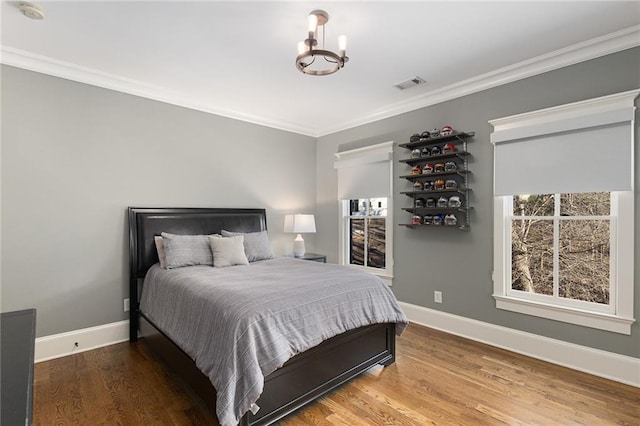 bedroom featuring crown molding, wood-type flooring, and an inviting chandelier