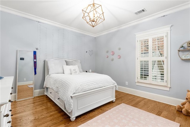 bedroom featuring light hardwood / wood-style flooring, ornamental molding, and a notable chandelier