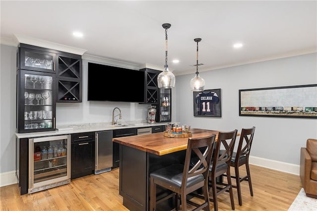 bar featuring sink, hanging light fixtures, beverage cooler, crown molding, and light hardwood / wood-style floors