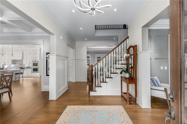 entrance foyer featuring coffered ceiling, beamed ceiling, crown molding, a chandelier, and wood-type flooring