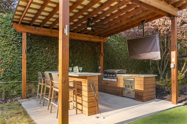 view of patio with a bar, grilling area, exterior kitchen, and ceiling fan