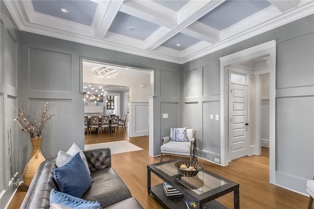 living room featuring hardwood / wood-style floors, beamed ceiling, coffered ceiling, and ornamental molding