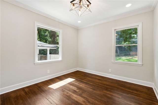 spare room with dark hardwood / wood-style floors, an inviting chandelier, and crown molding