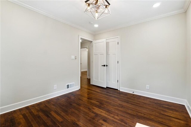 spare room featuring dark hardwood / wood-style floors, crown molding, and an inviting chandelier