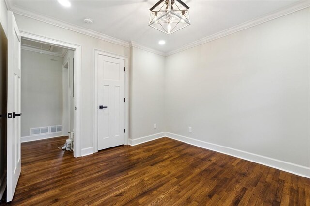 spare room with a chandelier, dark hardwood / wood-style floors, and ornamental molding