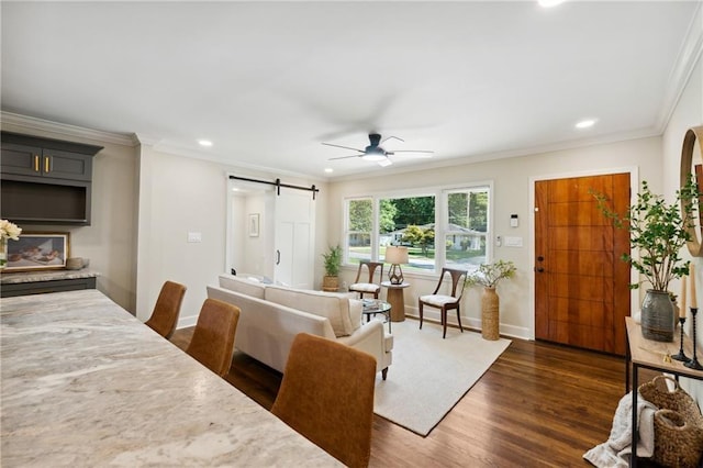 living room with a barn door, crown molding, ceiling fan, and dark wood-type flooring