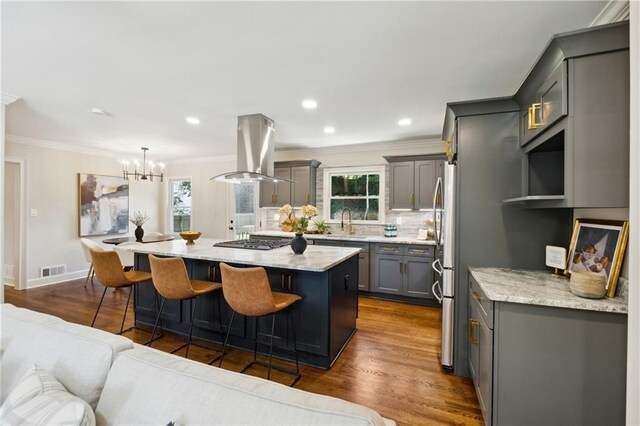 kitchen featuring gray cabinets, island range hood, a kitchen island, and a wealth of natural light