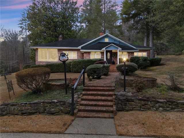 view of front of property featuring a chimney and brick siding