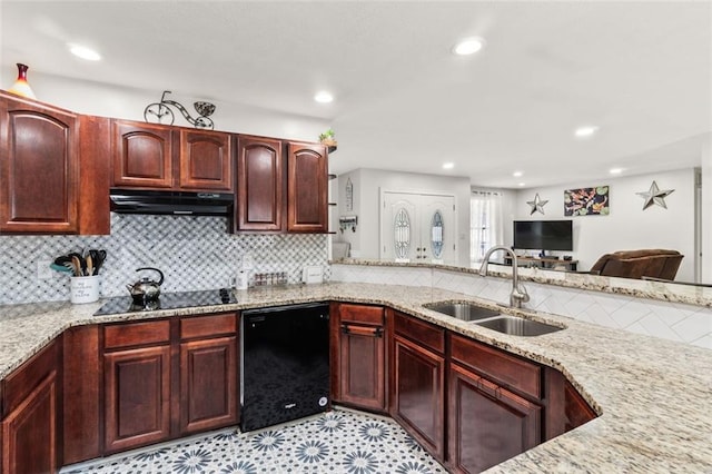 kitchen with light stone counters, a sink, black appliances, backsplash, and under cabinet range hood