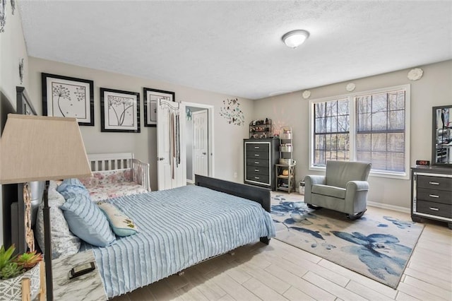 bedroom featuring wood finished floors, a textured ceiling, and baseboards
