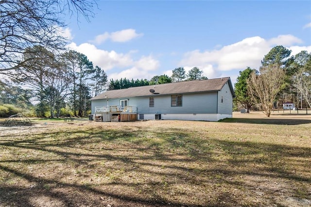 rear view of house featuring a lawn and a deck
