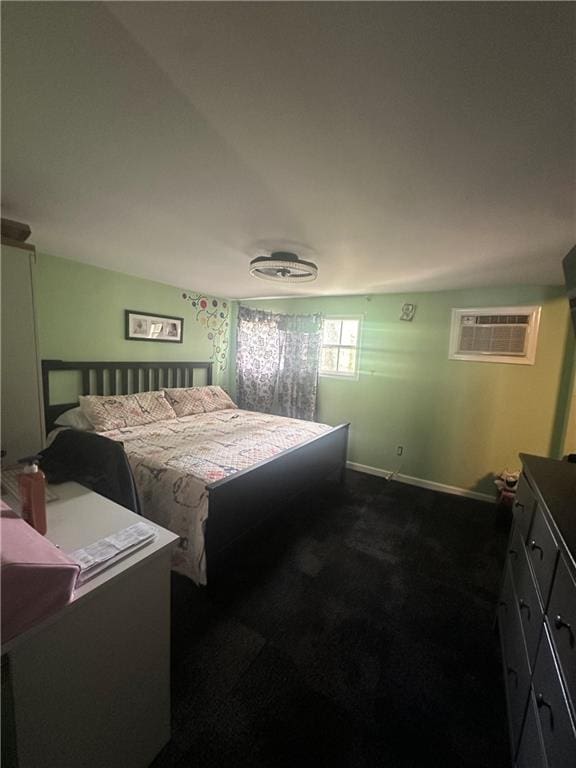 bedroom featuring baseboards, dark carpet, and an AC wall unit