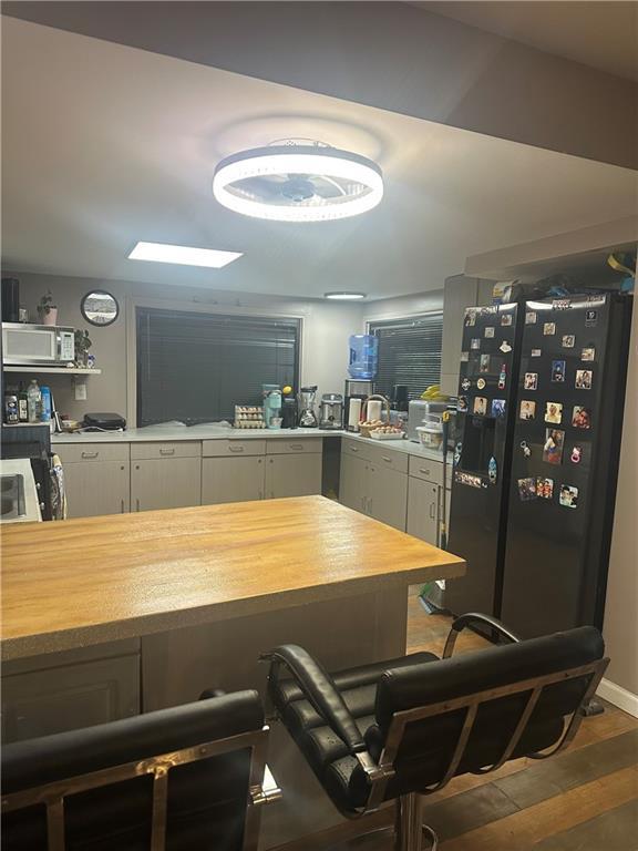 kitchen featuring freestanding refrigerator, white cabinets, white microwave, wood counters, and dark wood-type flooring