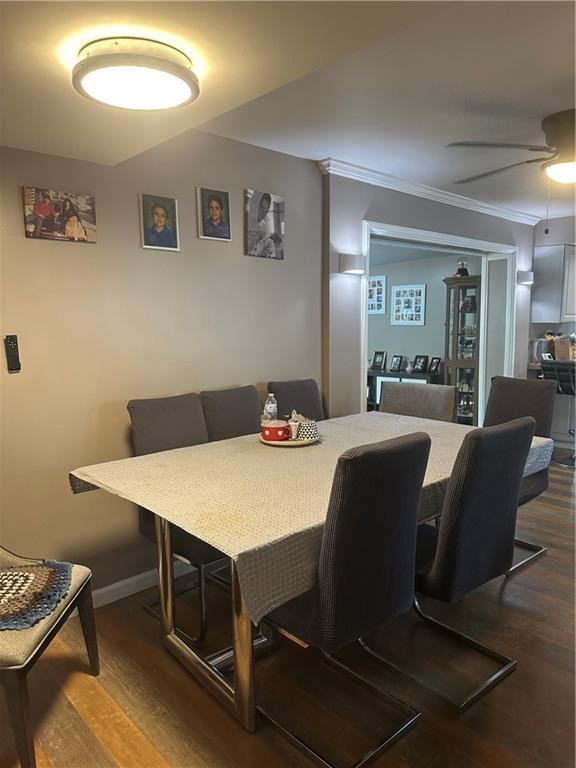 dining area with crown molding, baseboards, a ceiling fan, and dark wood-style flooring