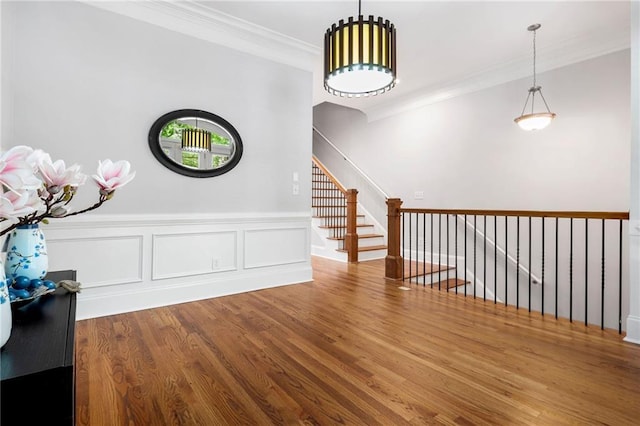 stairs featuring crown molding, wood finished floors, and a wainscoted wall