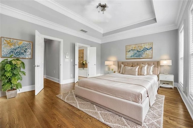 bedroom featuring baseboards, crown molding, wood finished floors, and a raised ceiling