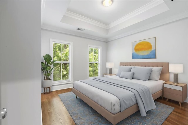 bedroom featuring a raised ceiling, wood finished floors, and ornamental molding