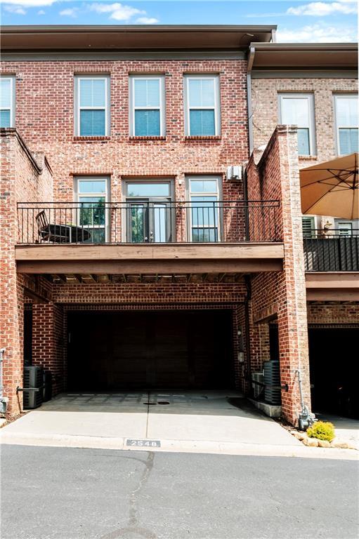 rear view of property with brick siding, a garage, and central air condition unit
