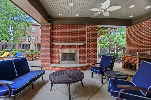 view of patio / terrace with fence, ceiling fan, an outdoor living space with a fireplace, and a sink