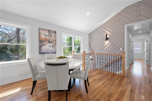 dining room featuring wood-type flooring, attic access, and a healthy amount of sunlight