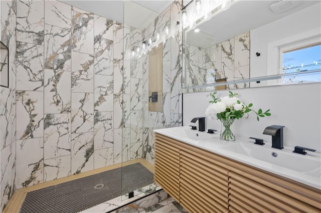 bathroom with double vanity, a marble finish shower, and a sink