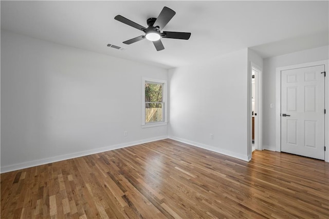 empty room with a ceiling fan, visible vents, baseboards, and wood finished floors