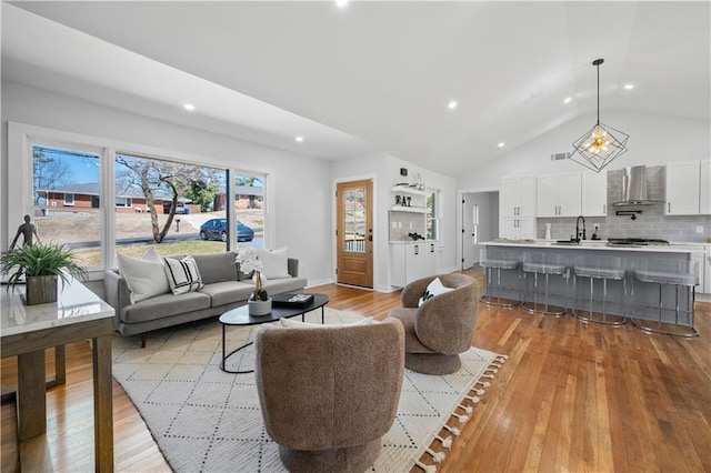 living room with high vaulted ceiling, light wood-style flooring, recessed lighting, visible vents, and baseboards