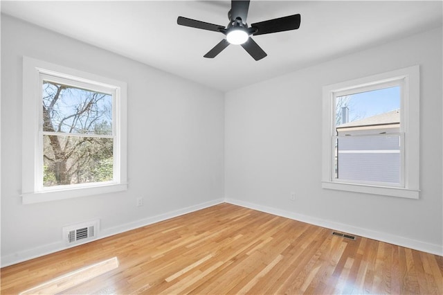 unfurnished room featuring a ceiling fan, wood finished floors, visible vents, and baseboards